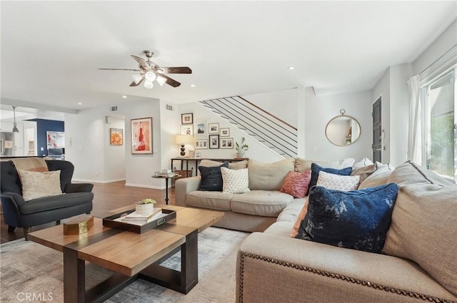 living area featuring stairs, baseboards, light wood-style flooring, and recessed lighting