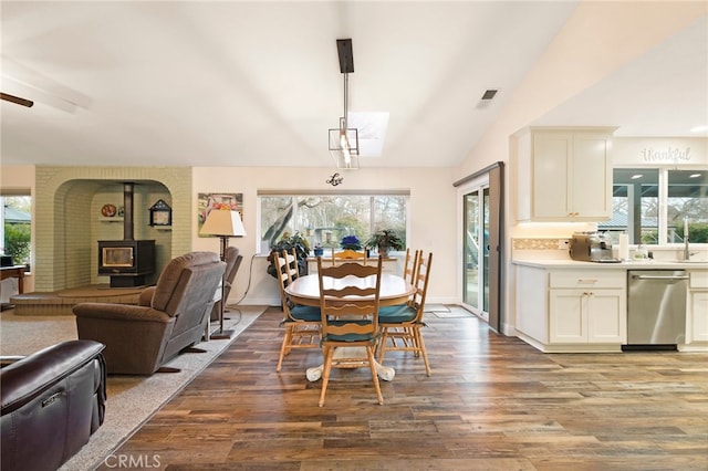 dining room featuring a wood stove, hardwood / wood-style floors, and vaulted ceiling