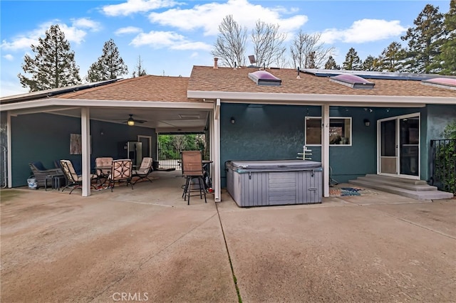 rear view of property with ceiling fan, a patio, and a hot tub