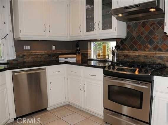 kitchen with white cabinetry, stainless steel appliances, decorative backsplash, and light tile patterned floors