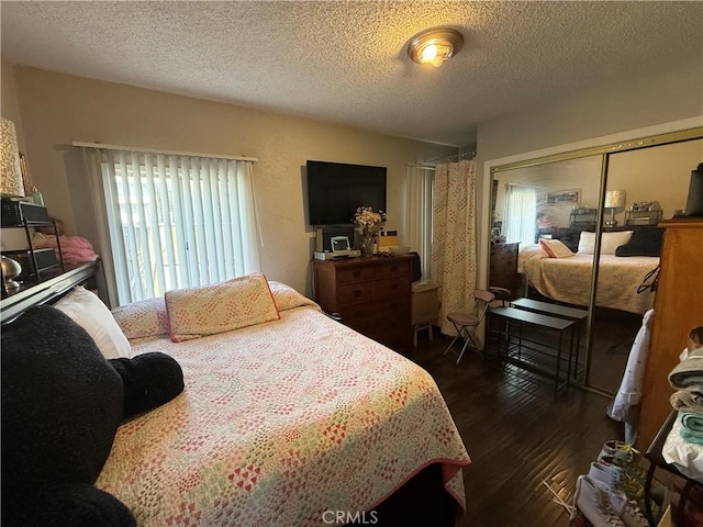 bedroom featuring dark wood-type flooring, a textured ceiling, and a closet