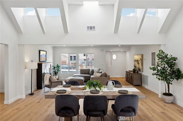 dining space featuring a high ceiling and light hardwood / wood-style floors