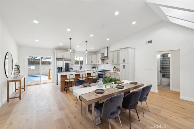 dining space with sink, light hardwood / wood-style flooring, and lofted ceiling with skylight