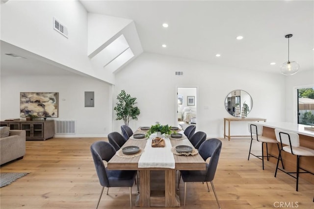 dining area with high vaulted ceiling, electric panel, and light wood-type flooring