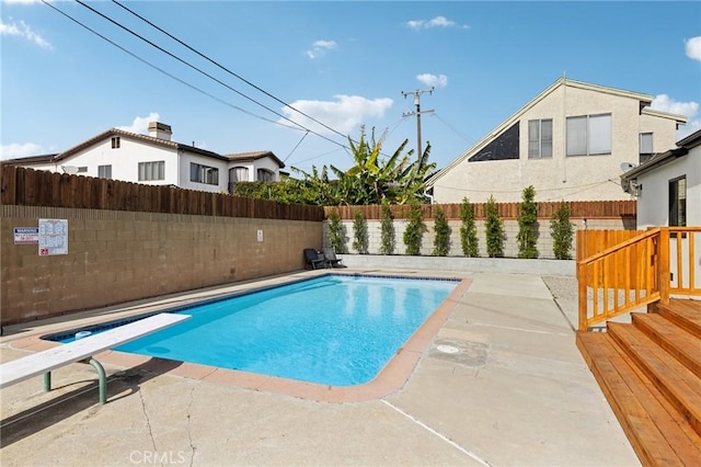 view of swimming pool with a diving board and a patio