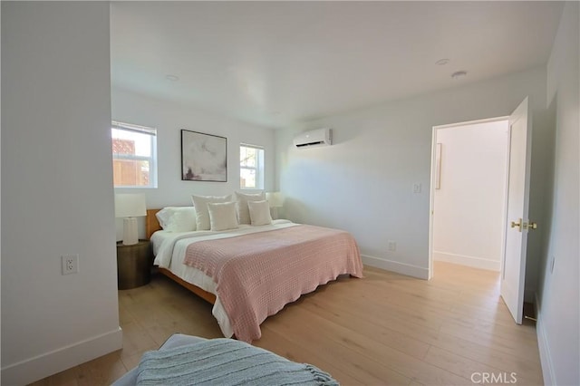 bedroom featuring a wall mounted AC and light wood-type flooring