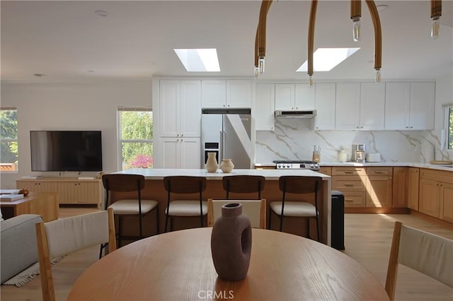 kitchen featuring a healthy amount of sunlight, high quality fridge, white cabinets, and backsplash