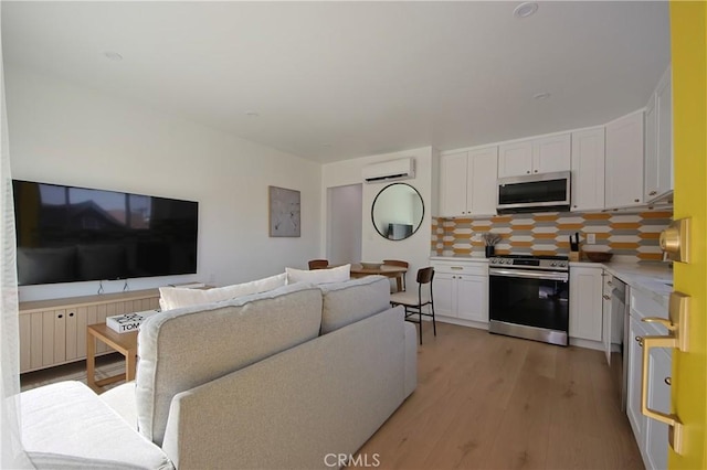 living room featuring light hardwood / wood-style flooring and a wall unit AC