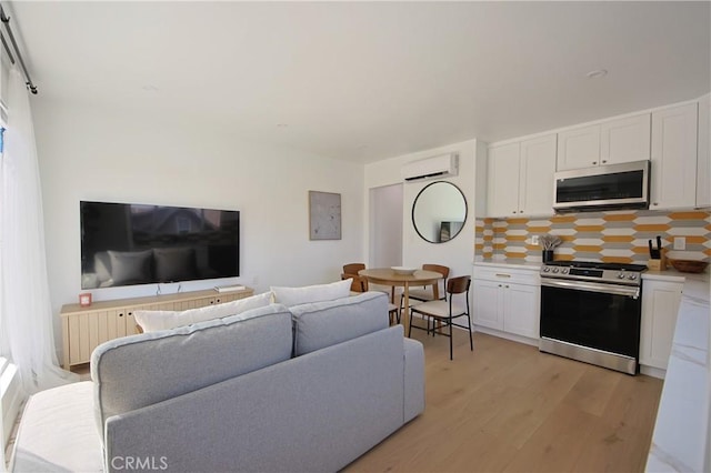 living room featuring electric panel, light wood-type flooring, and an AC wall unit