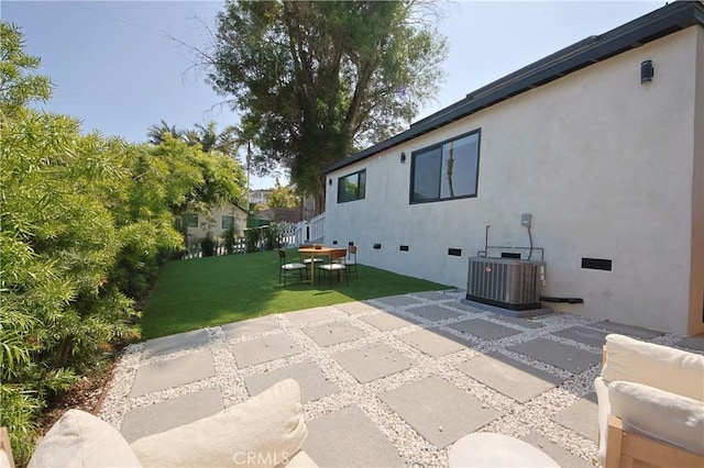 rear view of house with cooling unit, a patio area, and a lawn