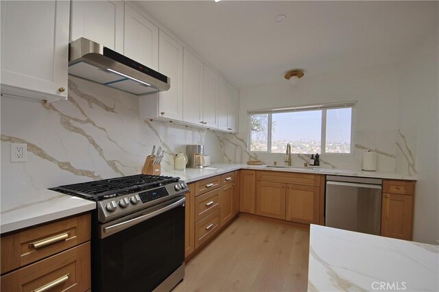 kitchen featuring sink, light wood-type flooring, stainless steel appliances, light stone countertops, and white cabinets