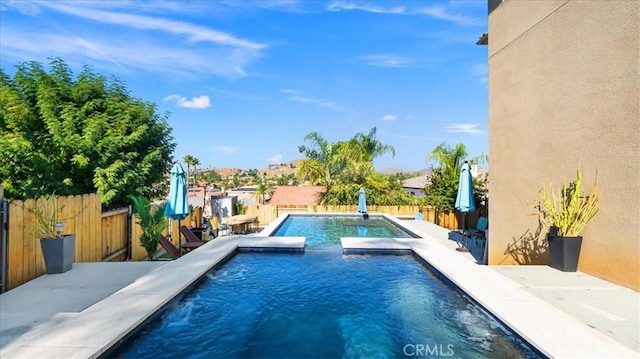 view of swimming pool featuring a patio area, a fenced backyard, and a pool with connected hot tub