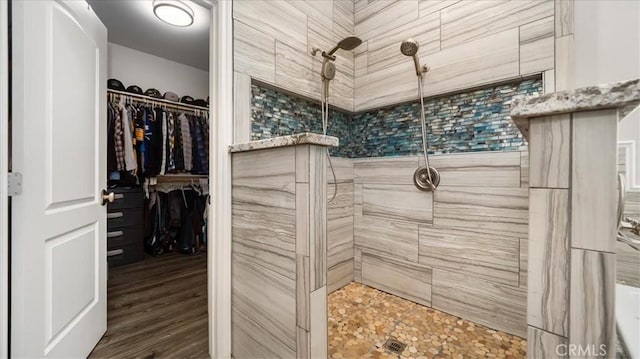 bathroom featuring a walk in closet, tiled shower, and wood finished floors