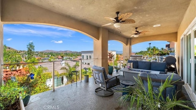 view of patio / terrace featuring a ceiling fan, an outdoor living space, a mountain view, and a balcony