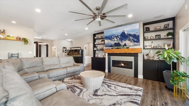 living area with wood finished floors, recessed lighting, a glass covered fireplace, and built in features