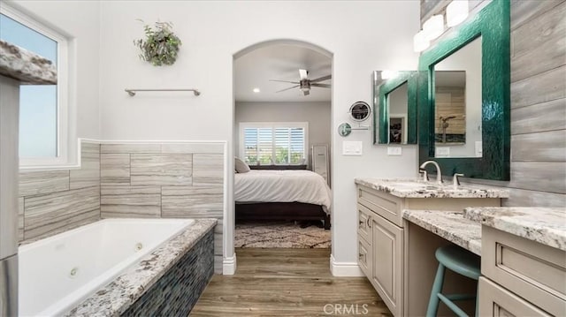 ensuite bathroom with ceiling fan, vanity, ensuite bath, wood finished floors, and a whirlpool tub