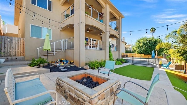 back of house with a patio area, an outdoor fire pit, fence, and stucco siding