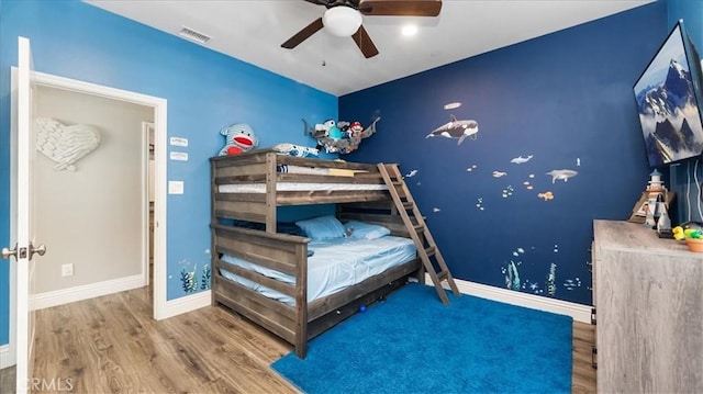 bedroom with visible vents, ceiling fan, baseboards, and wood finished floors