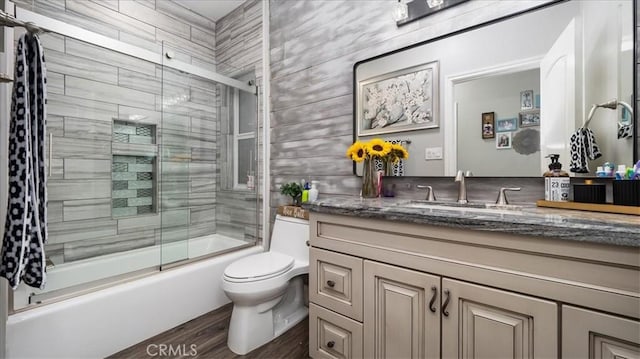 full bath with combined bath / shower with glass door, vanity, toilet, and wood finished floors