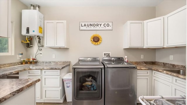 washroom with a sink, cabinet space, water heater, and washer and dryer