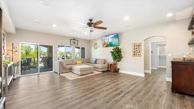 living area with light wood finished floors, baseboards, arched walkways, a ceiling fan, and recessed lighting