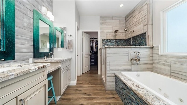 bathroom featuring tiled shower, wood finished floors, a whirlpool tub, a walk in closet, and vanity