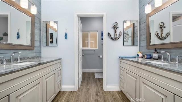 bathroom with baseboards, two vanities, a sink, and wood finished floors