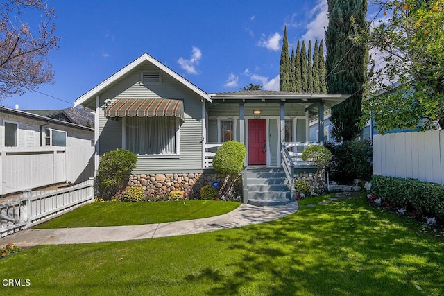 view of front of home featuring covered porch, fence, and a front yard