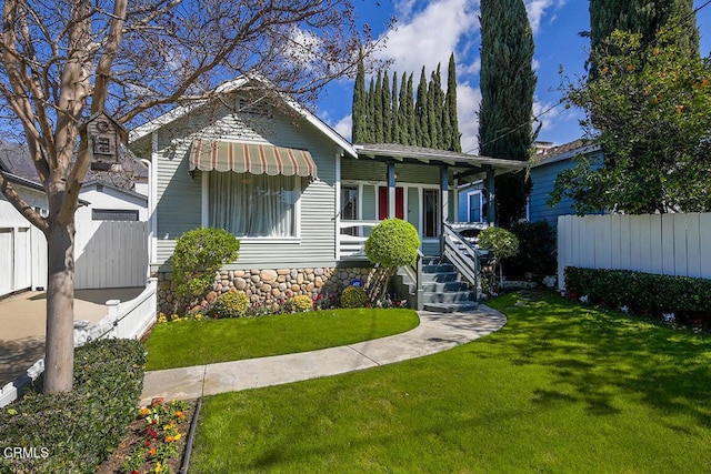 view of front of house with covered porch, fence, and a front lawn