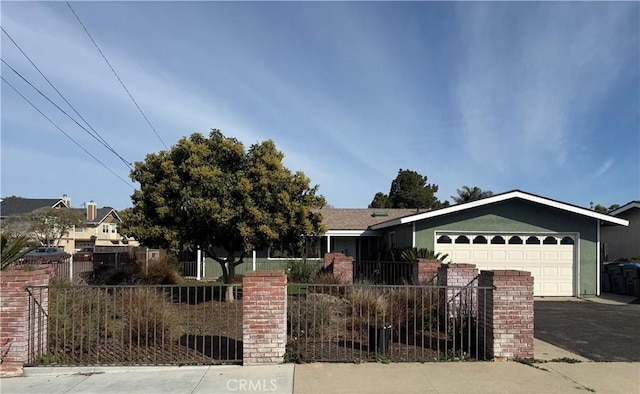 ranch-style house featuring driveway, a fenced front yard, an attached garage, and stucco siding