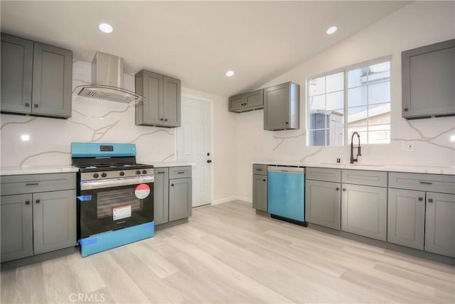 kitchen featuring wall chimney range hood, sink, appliances with stainless steel finishes, gray cabinetry, and vaulted ceiling