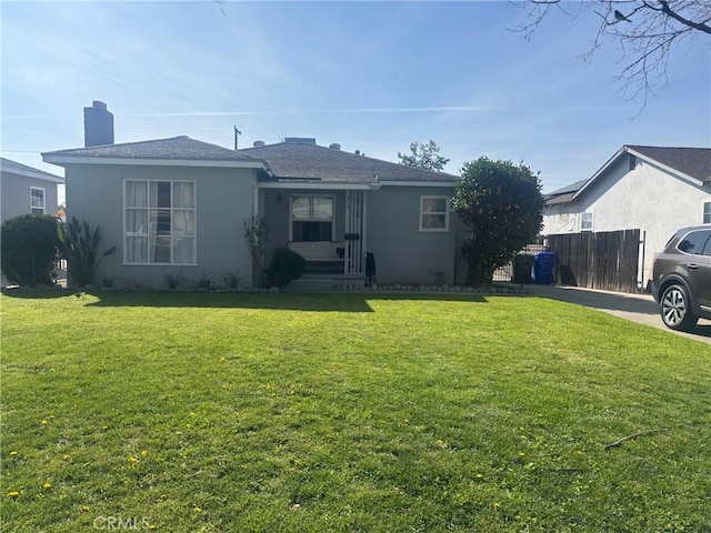 view of front of home featuring stucco siding, fence, and a front yard