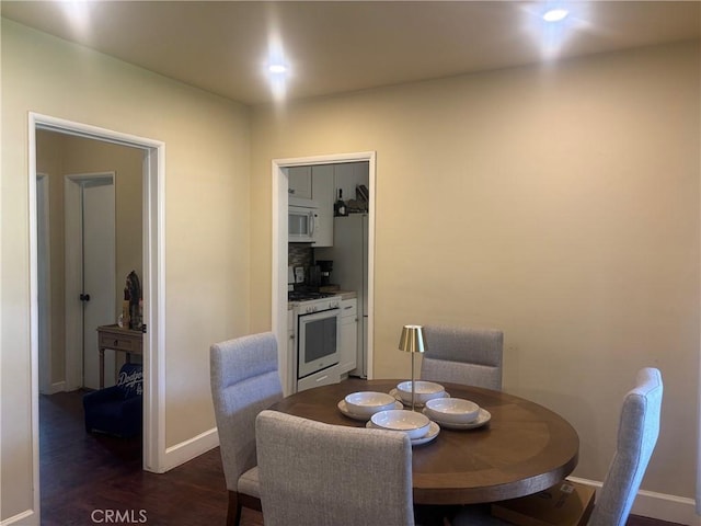 dining space with dark wood-style flooring and baseboards