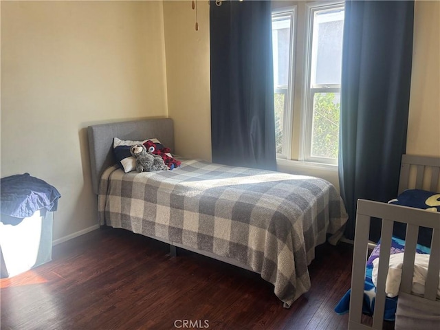 bedroom with dark wood finished floors and baseboards