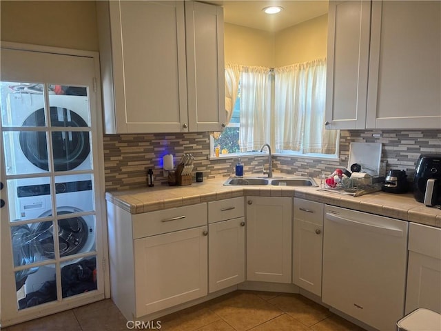 kitchen featuring dishwasher, a sink, tile counters, and white cabinets