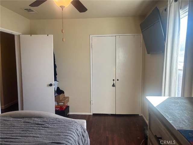 bedroom with ceiling fan, visible vents, dark wood finished floors, and a closet