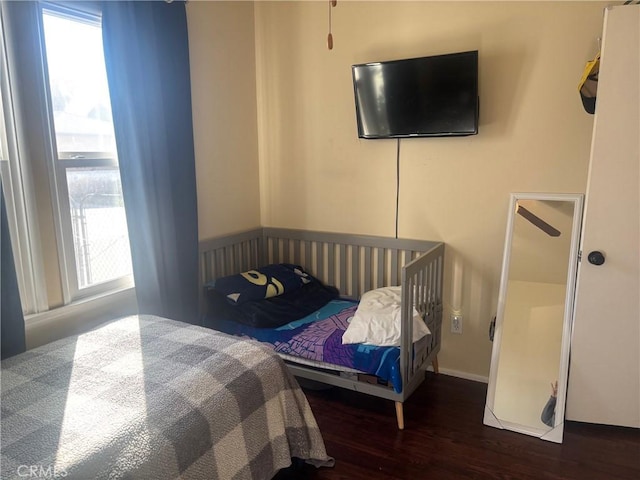 bedroom with multiple windows and wood finished floors