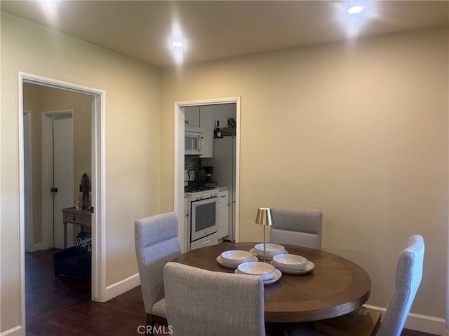 dining space featuring dark wood finished floors and baseboards