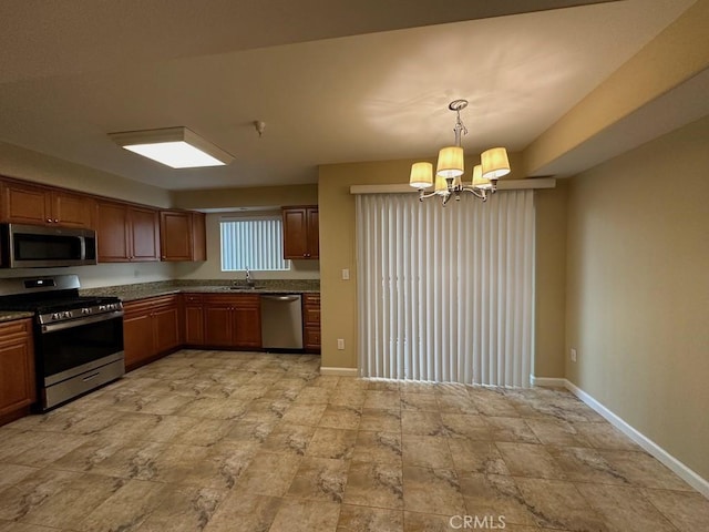 kitchen with an inviting chandelier, appliances with stainless steel finishes, decorative light fixtures, and sink