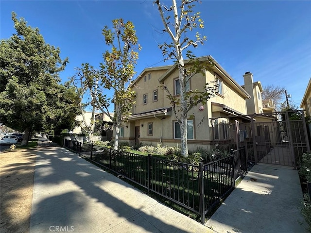 view of side of home featuring a fenced front yard, a residential view, a gate, and stucco siding