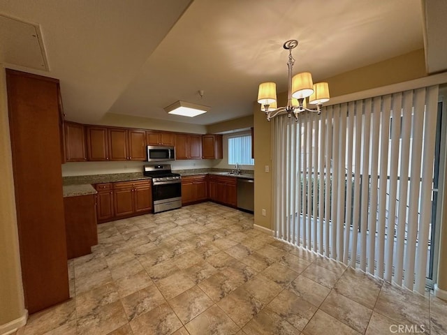 kitchen with stainless steel appliances, sink, pendant lighting, and an inviting chandelier