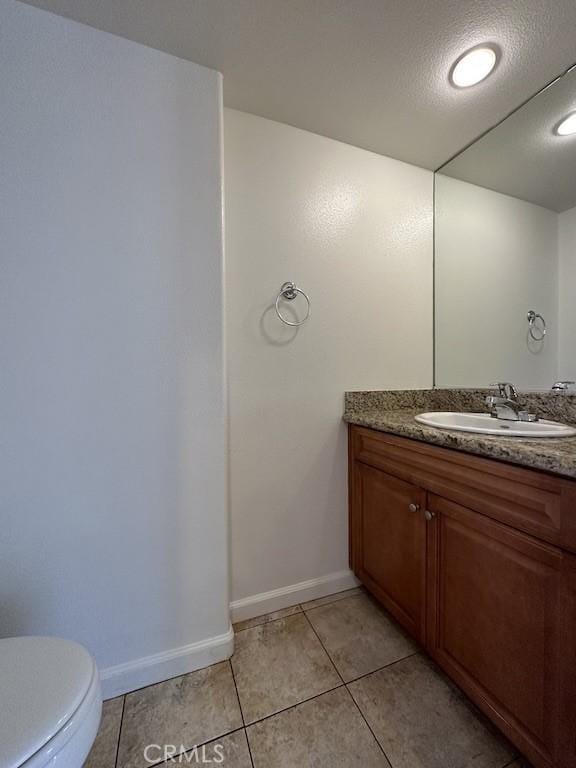 bathroom with tile patterned floors, toilet, vanity, and a textured ceiling