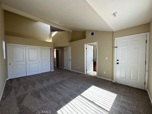 unfurnished bedroom featuring multiple closets, lofted ceiling, and dark colored carpet