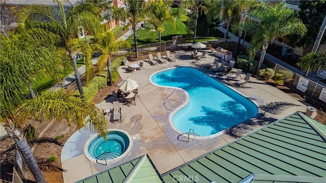 community pool with a patio area, fence, and a community hot tub