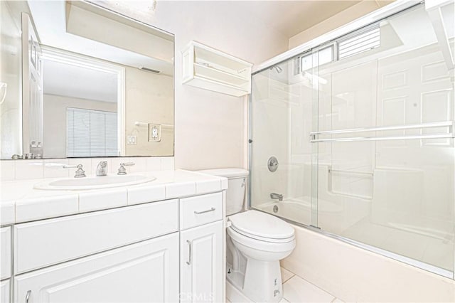 bathroom with shower / bath combination with glass door, tile patterned flooring, vanity, and toilet