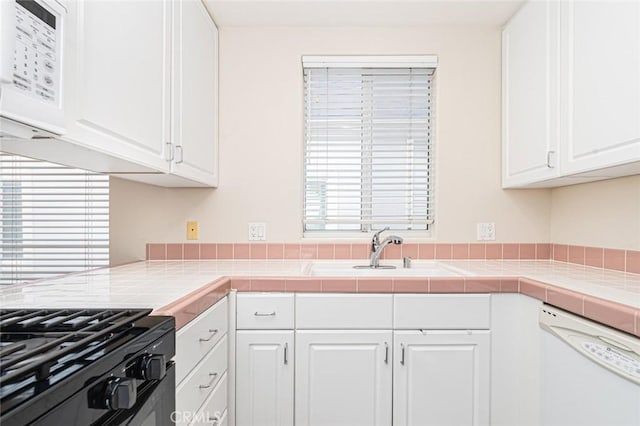 kitchen with tile countertops, white appliances, and white cabinetry