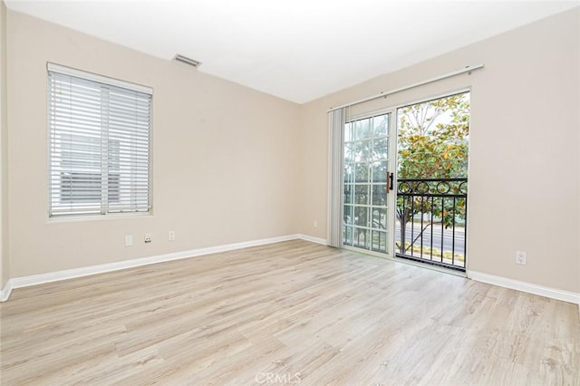 unfurnished room featuring visible vents, light wood-style flooring, and baseboards