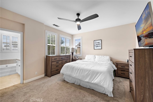 bedroom featuring light colored carpet, ceiling fan, and ensuite bath