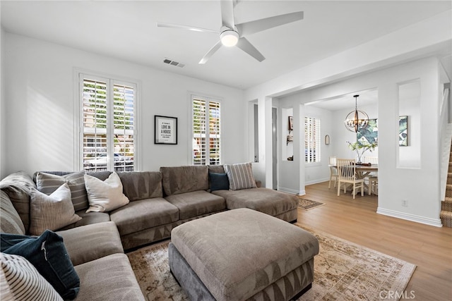 living room featuring wood-type flooring and ceiling fan with notable chandelier