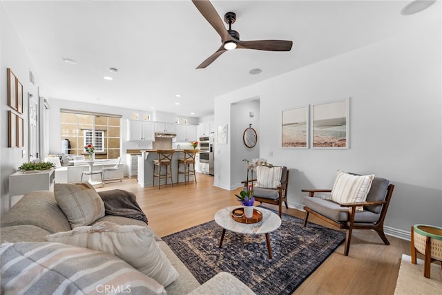 living room with ceiling fan and light hardwood / wood-style flooring